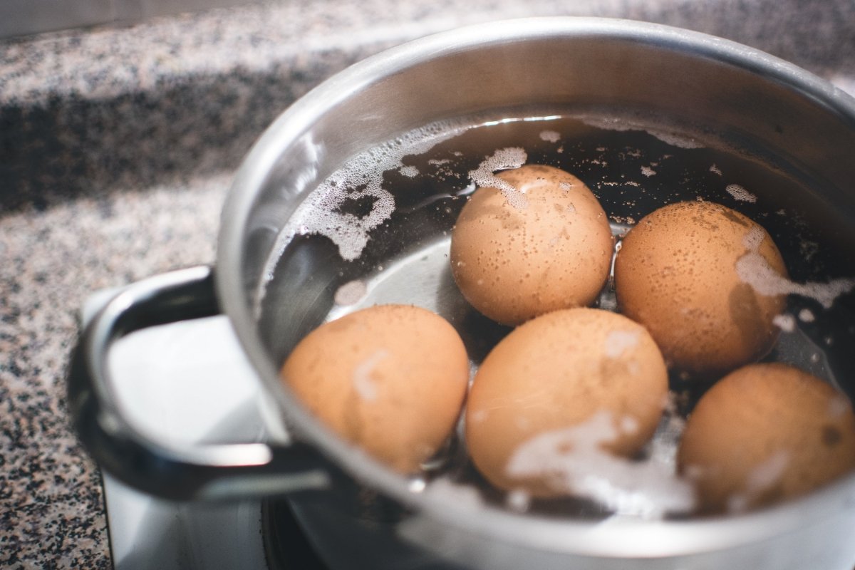 5 huevos con cáscara cociéndose con agua en el interior de una olla