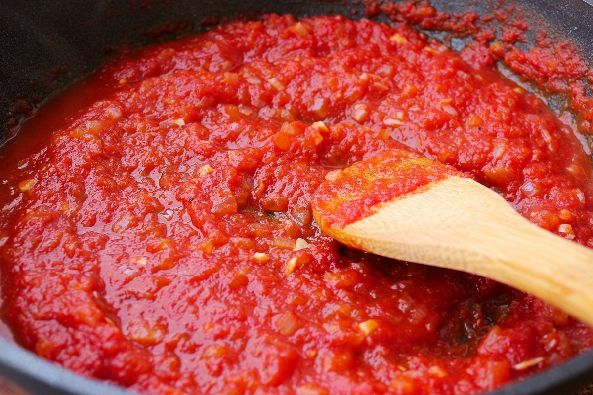 Adición a la salsa de tomate del del pimentón y del agua de la cocción