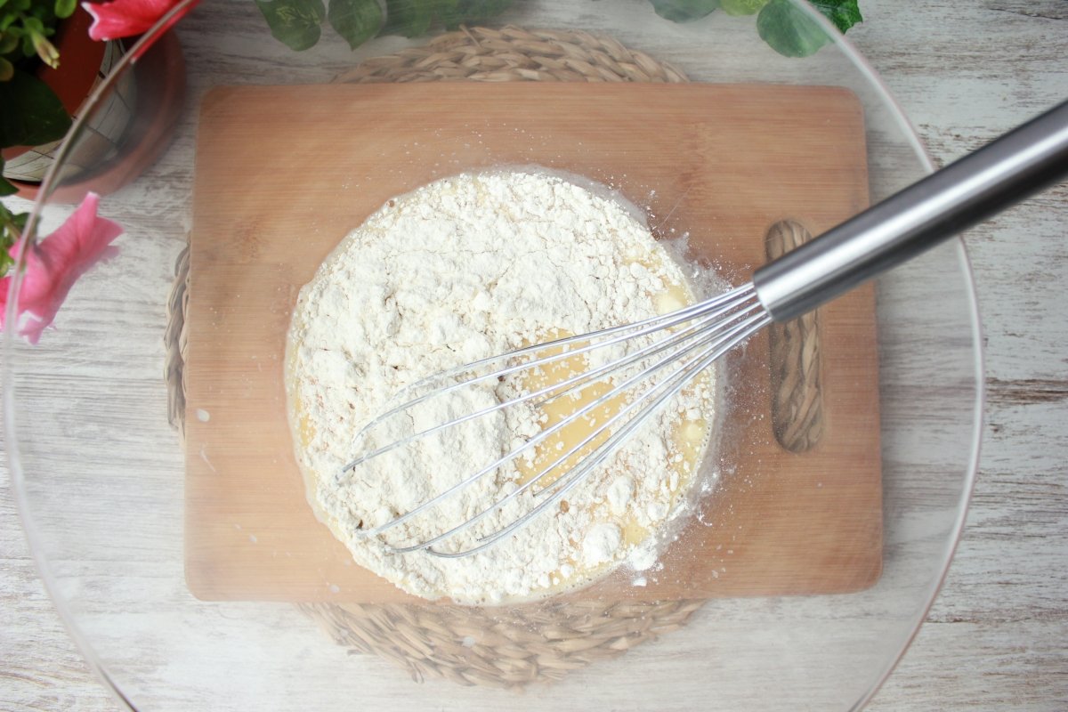 Adición de harina a la mezcla batida para hacer un clafoutis o tarta de cerezas