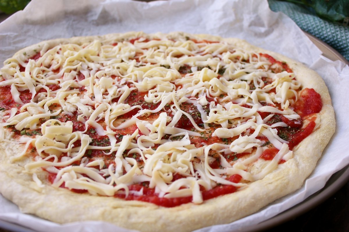 Adición de la mozzarella rallada a la base de la pizza