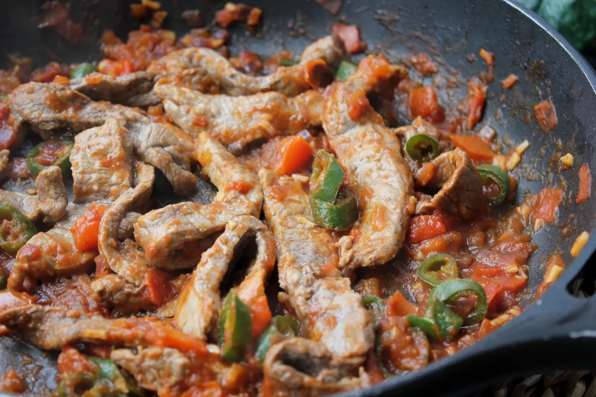 Adición de las tiras de ternera a la salsa para finalizar el bistec de res a la mexicana