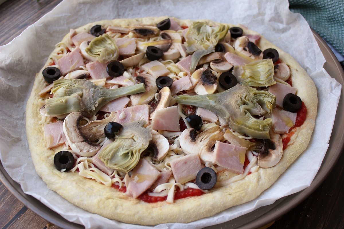 Adición de los demás ingredientes para crear la pizza caprichosa