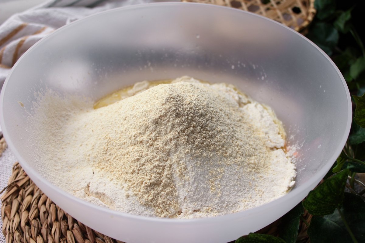 Adición de los ingredientes secos para hacer la masa de la pinsa romana