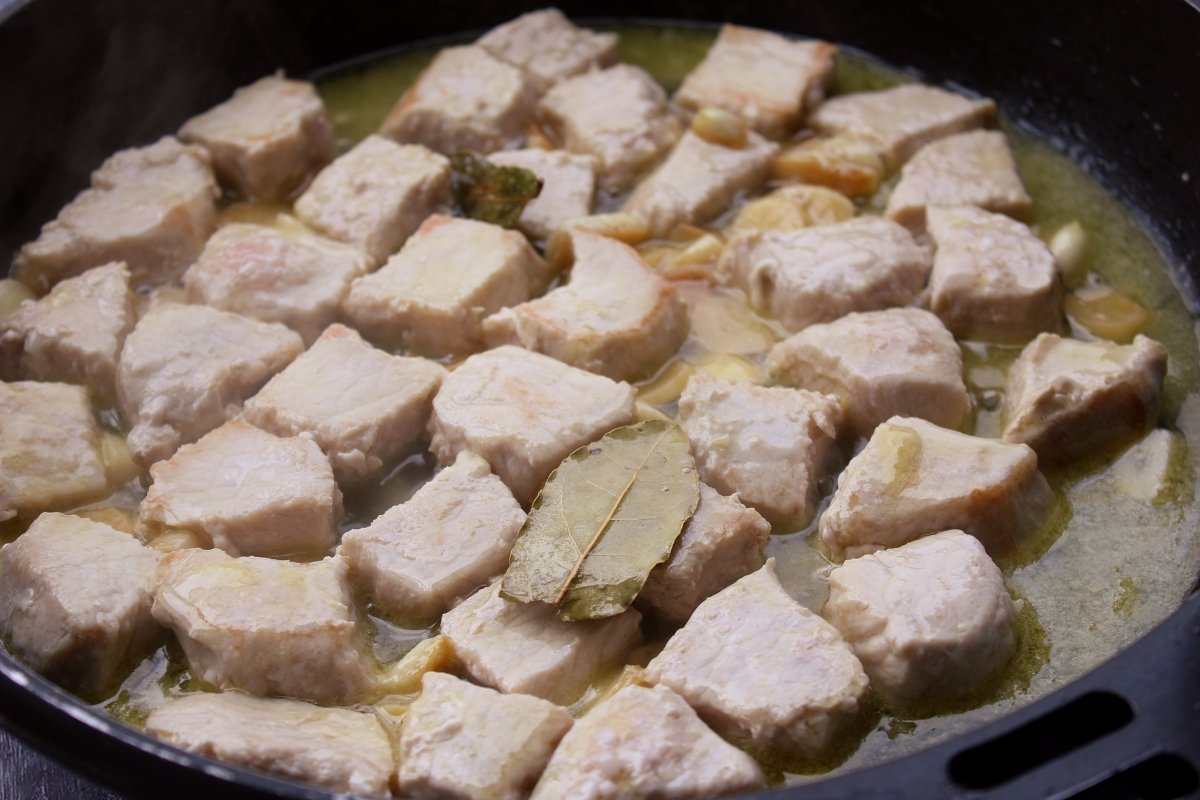 Adición del caldo de carne a la sartén con los tacos de lomo de cerdo