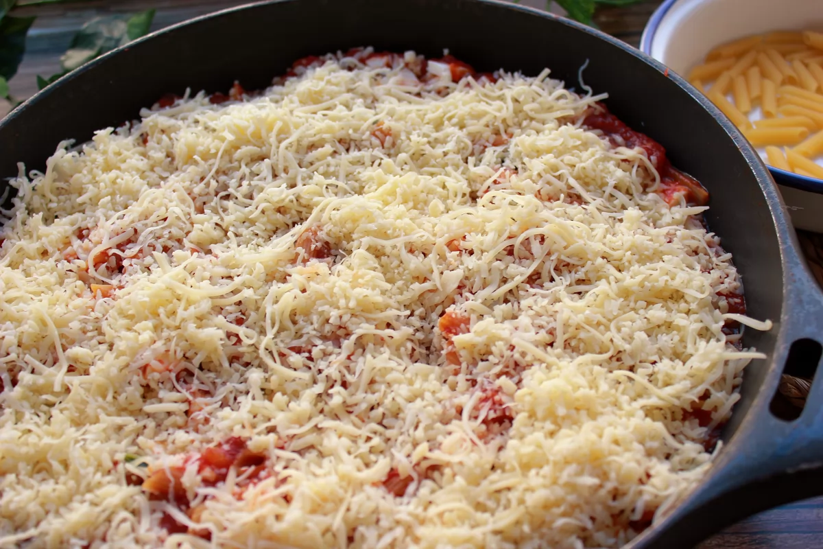 Adición del queso rallado a la fuente de los macarrones *