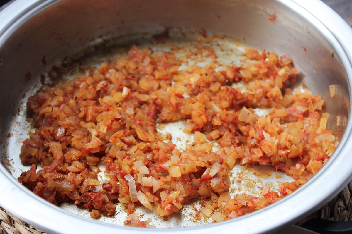Adición del tomate triturado y de los condimentos al sofrito de cebolla