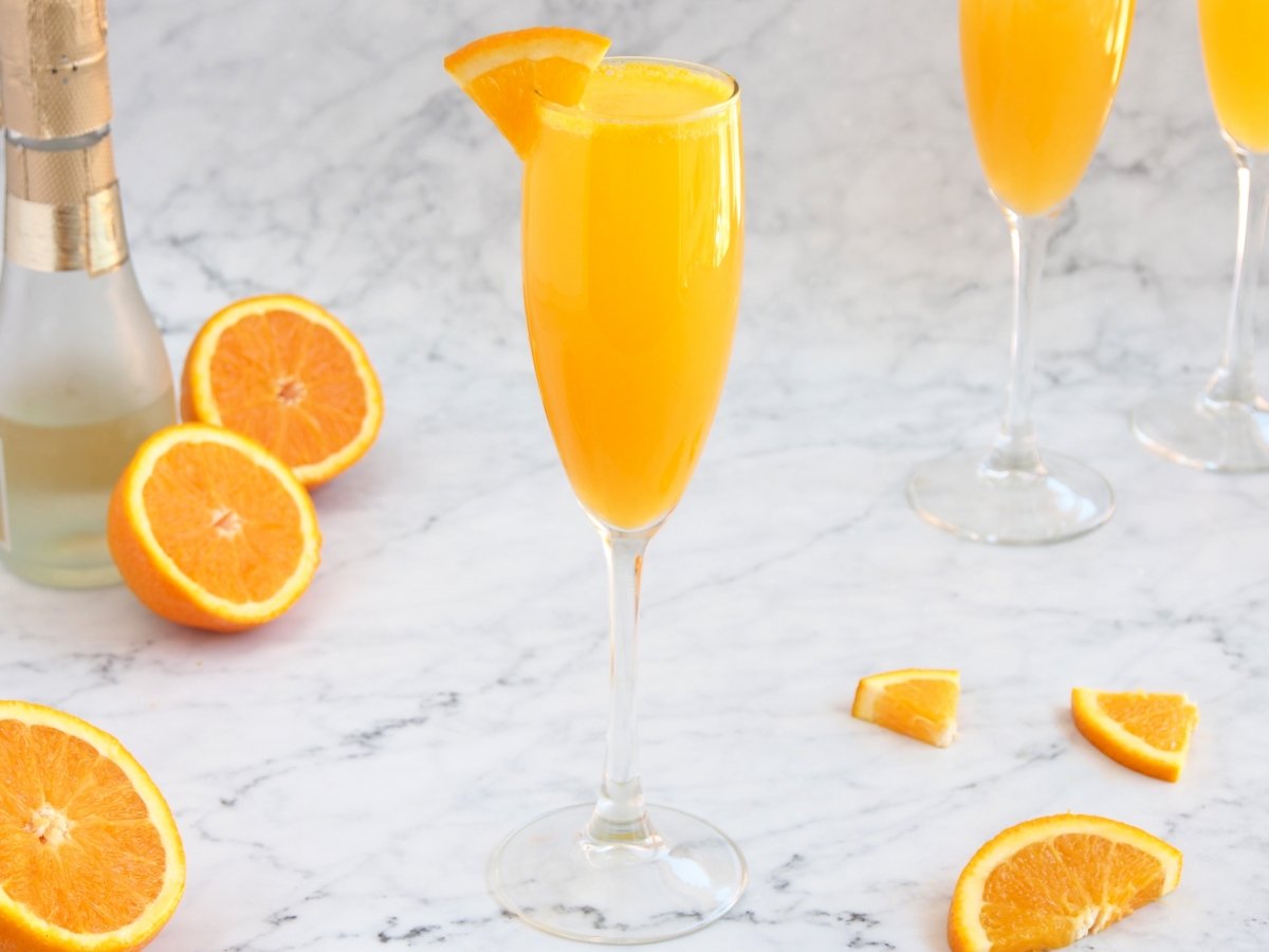 Adornar el cóctel mimosa con un trocito de naranja