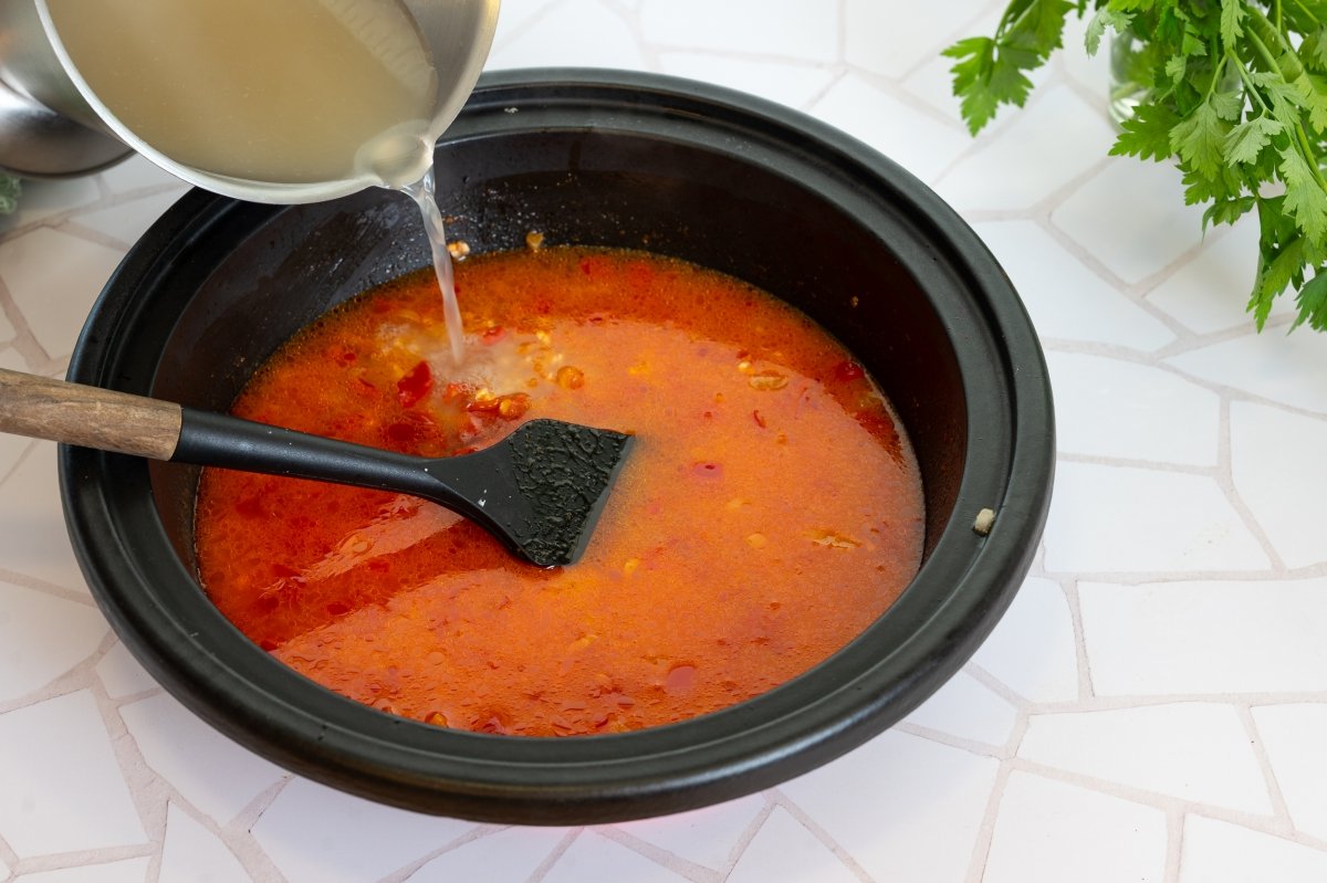 Agragando el caldo para hacer arroz caldoso con bacalao