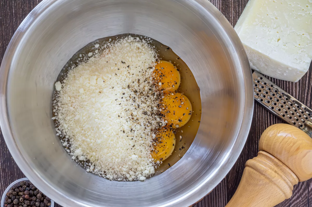 Agregar pecorino rallado y pimienta a la salsa carbonara