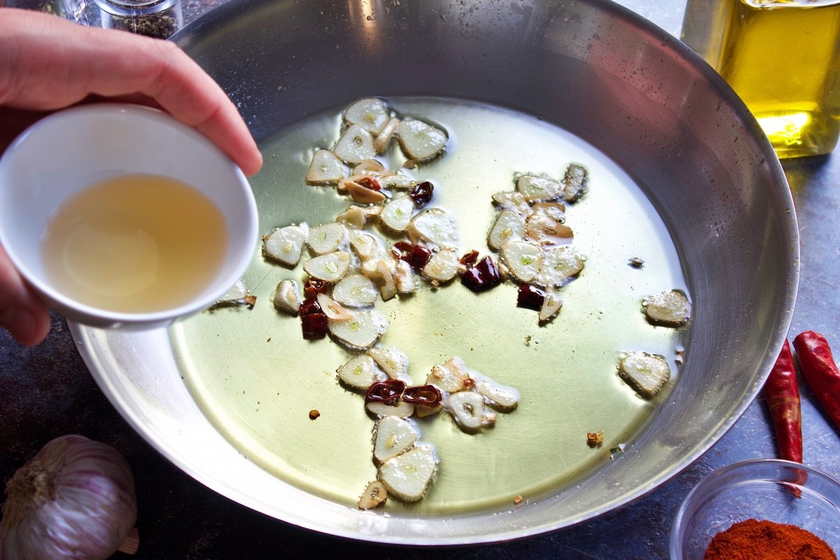 Añadiendo a la salsa de la lubina a la bilbaína el vinagre