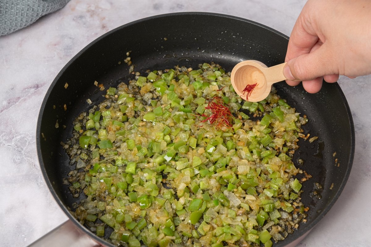 Añadiendo azafrán al sofrito de las alubias con almejas