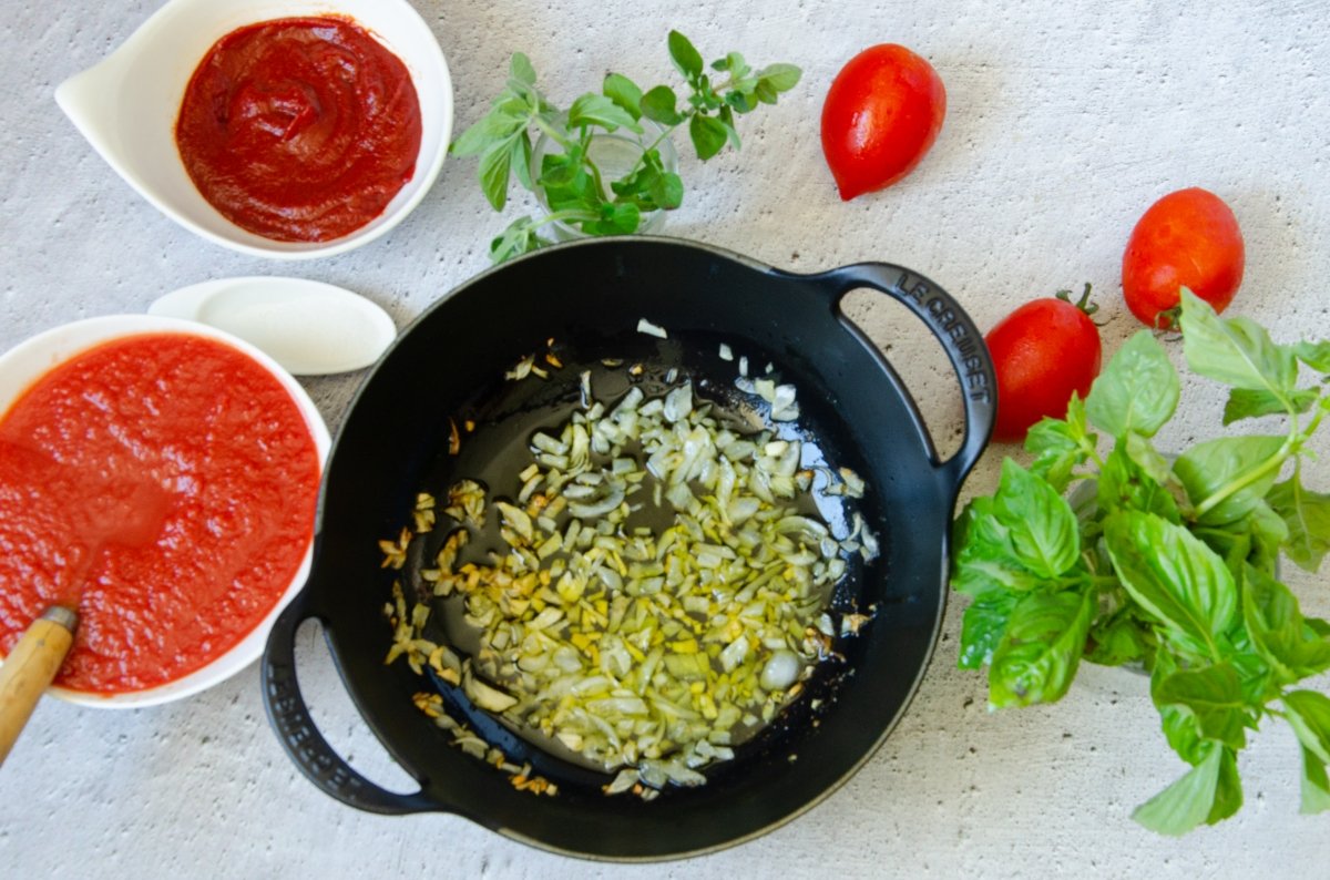 Añadiendo el tomate a la cebolla pochada para hacer la salsa marinara