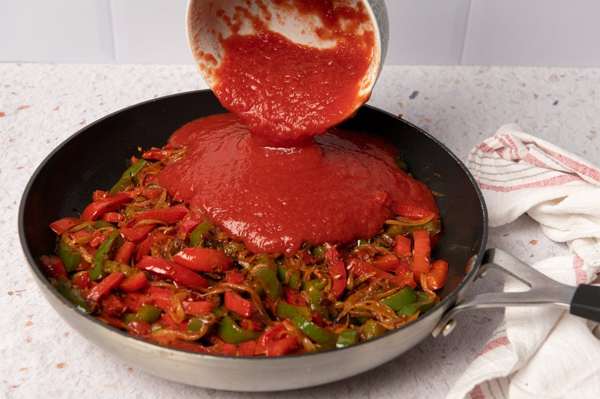 Añadiendo el tomate a la sartén de shakshuka