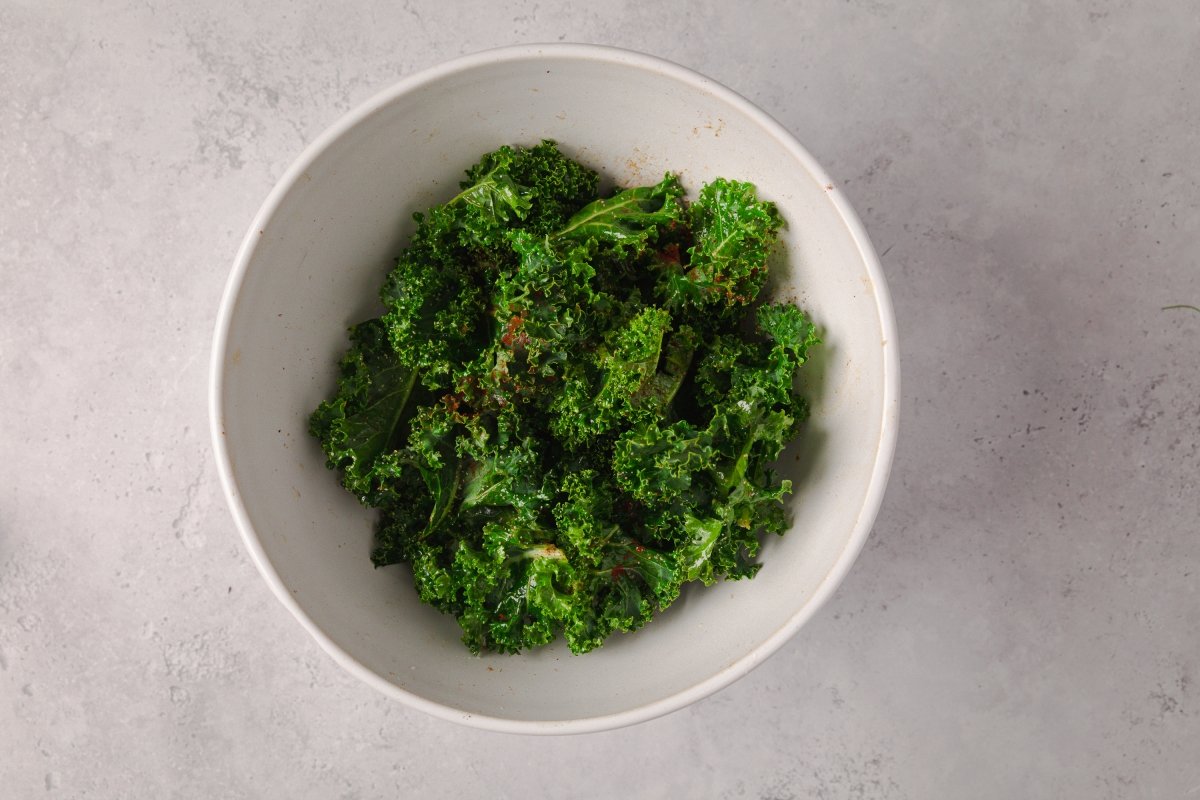 Añadiendo especias a los chips de kale al horno