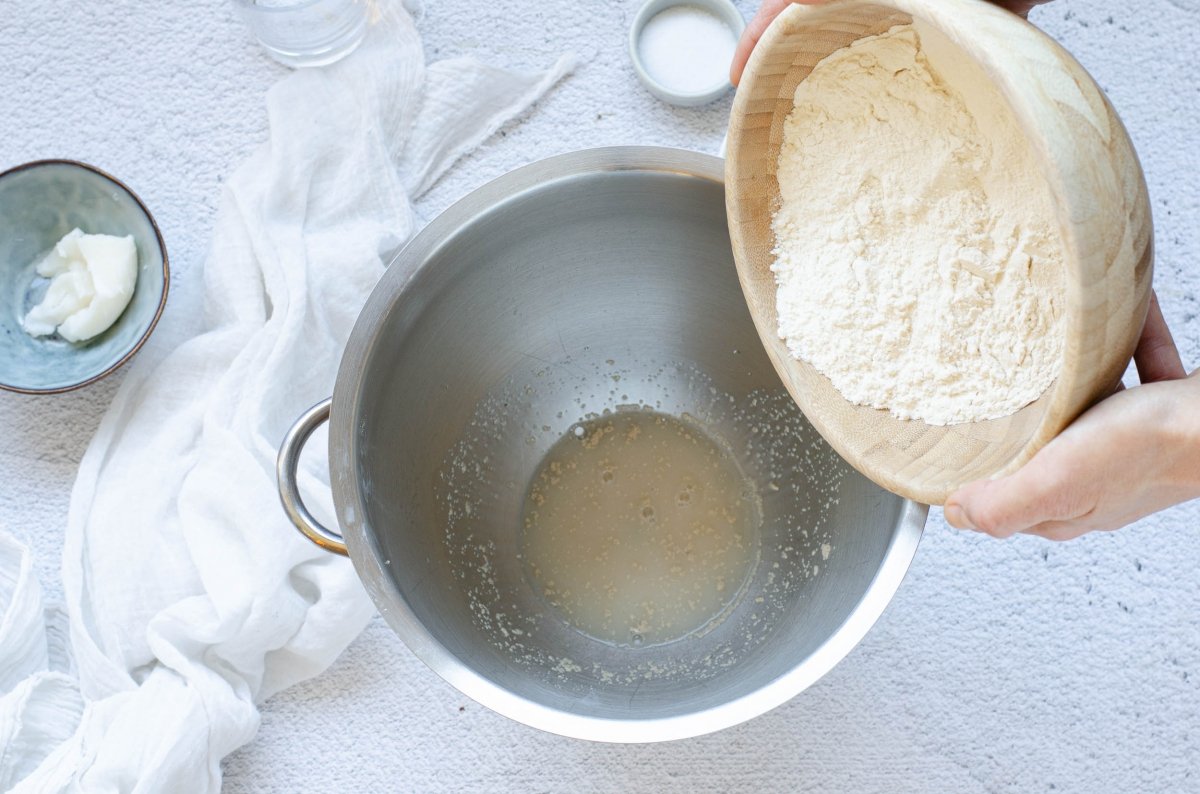 Adding flour to the mixer to make Mallorcan ensaimada