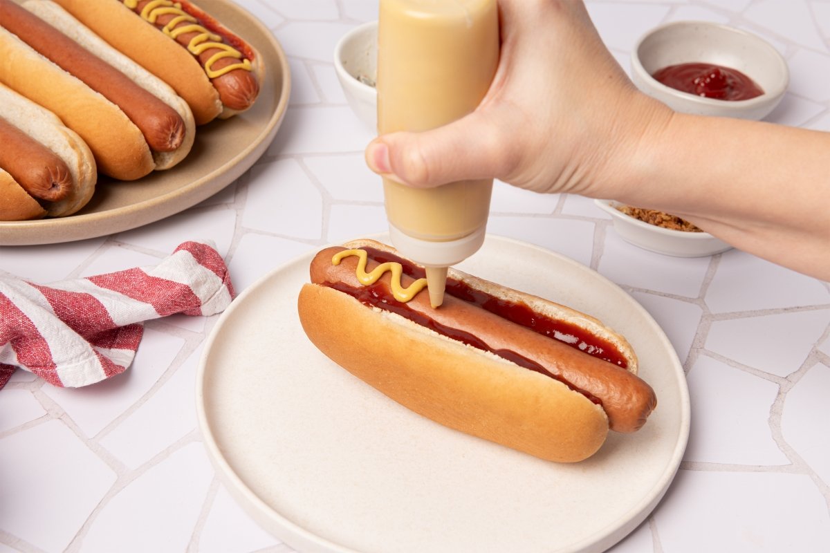 Añadiendo ketchup y mostaza al hot dog