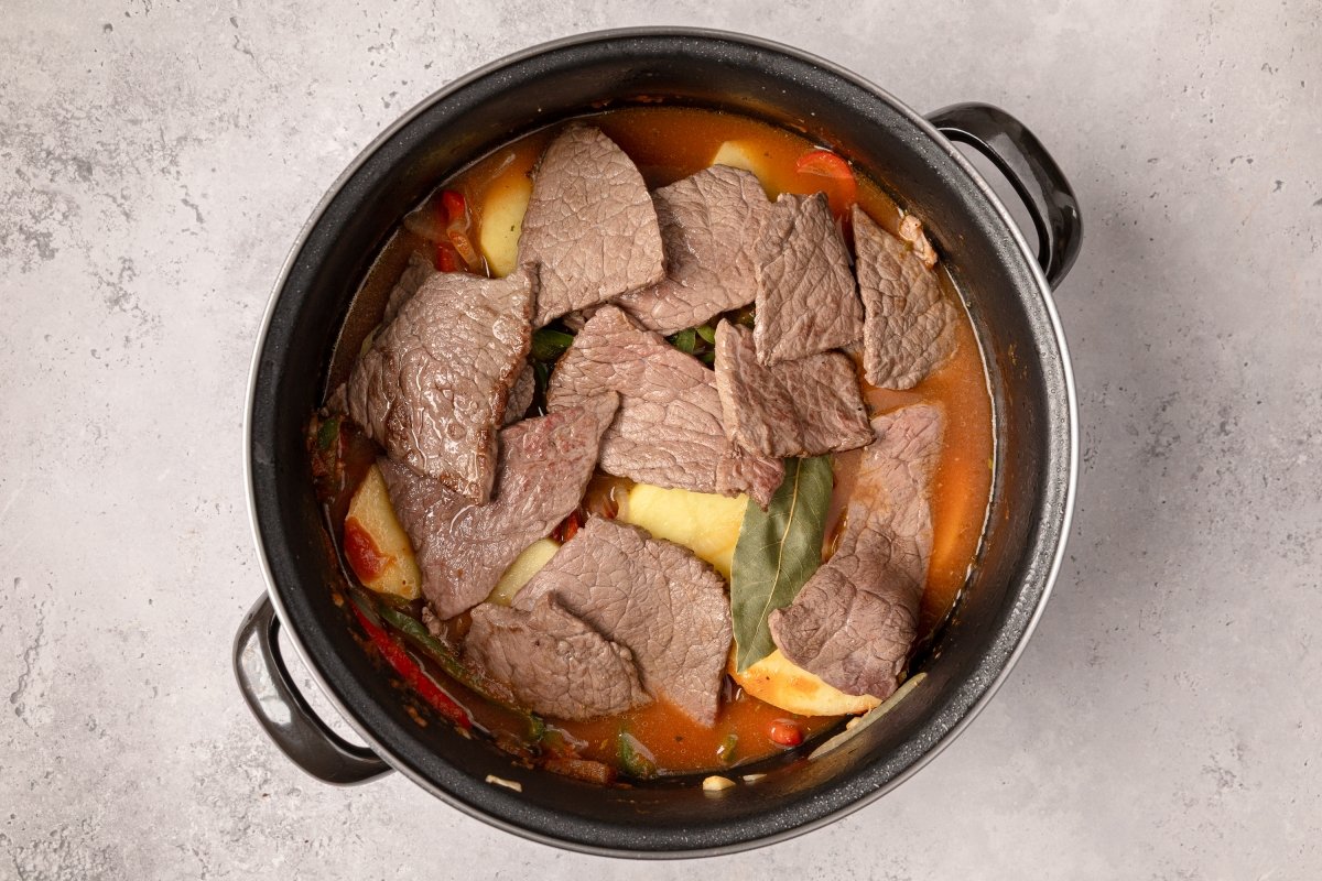 Añadiendo la carne para los bifes a la criolla
