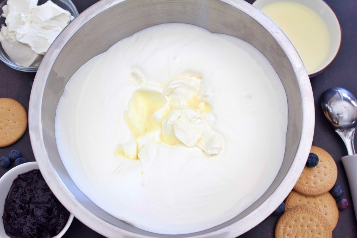 Adding the condensed milk and spreadable cheese to continue making the cheesecake ice cream