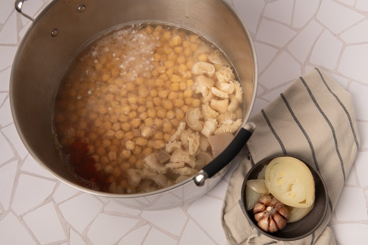 Añadiendo la legumbre a la olla de callos con garbanzos