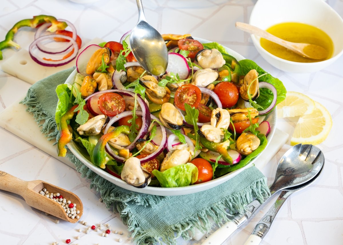 Añadiendo la vinagreta a la ensalada de mejillones