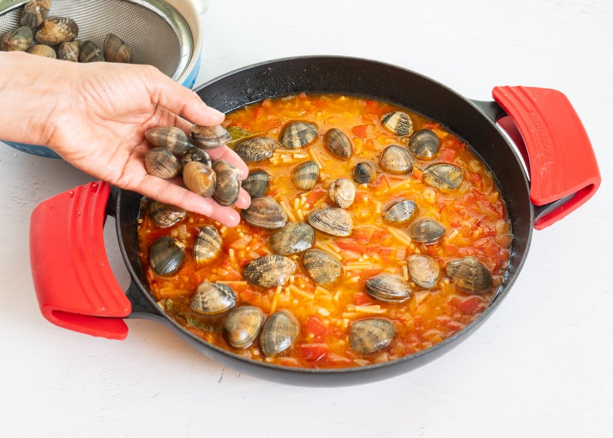 Añadiendo las almejas para hacer fideos con almejas