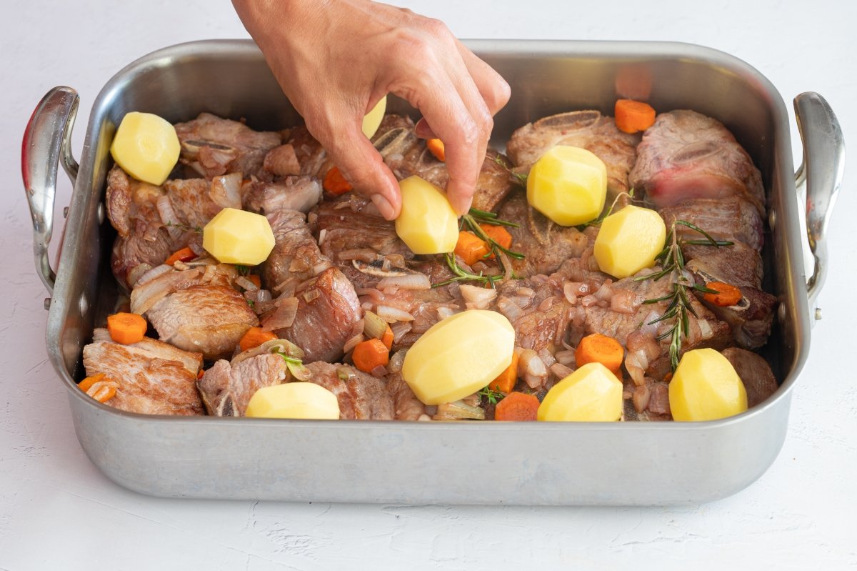 Añadiendo las patatas para hacer falda de ternera asada