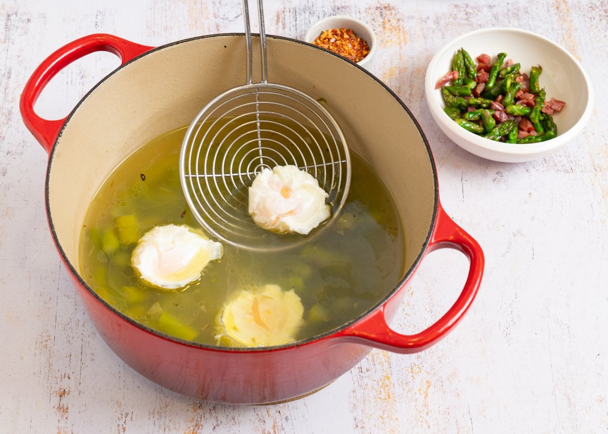 Añadiendo los huevos escalfados a la sopa de espárragos trigueros
