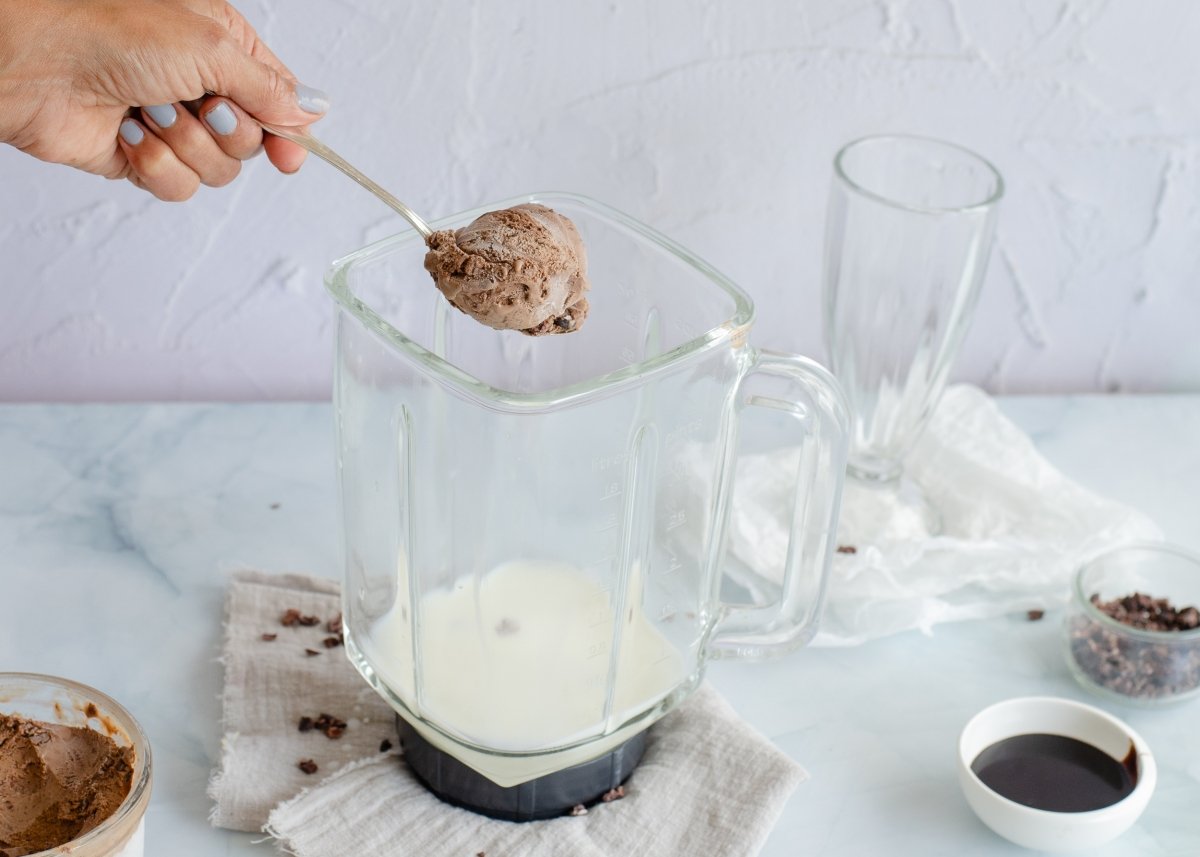 Añadiendo los ingredientes en el vaso para hacer milkshake de chocolate