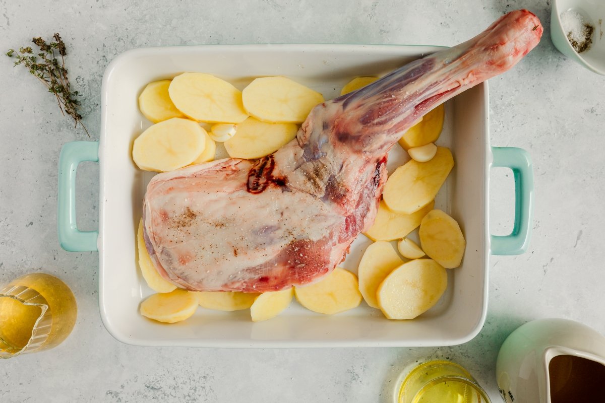 Añadiendo patatas al cordero asado