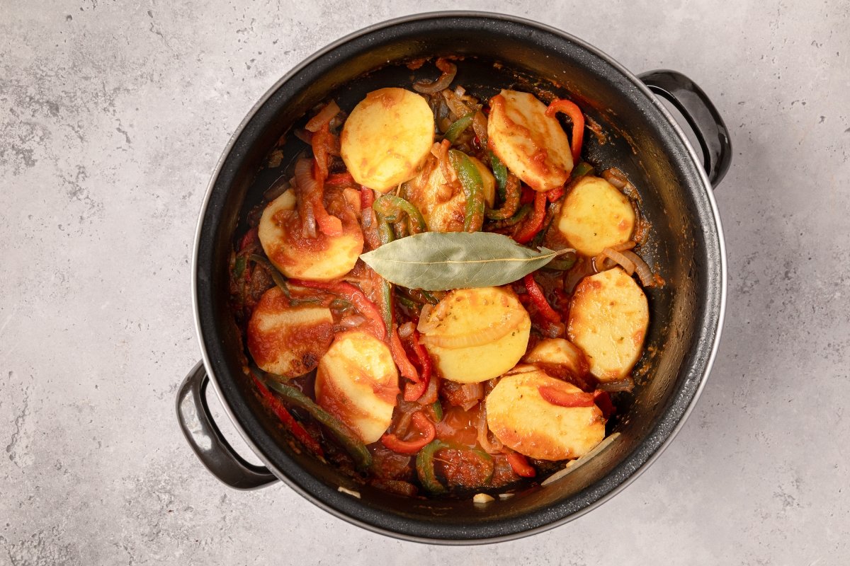 Añadiendo patatas y tomate a los bifes a la criolla