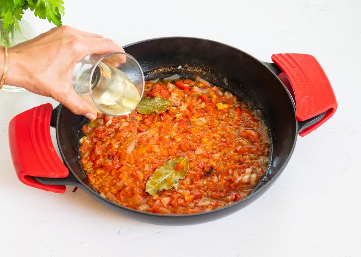 Añadiendo vino blanco para hacer fideos con almejas