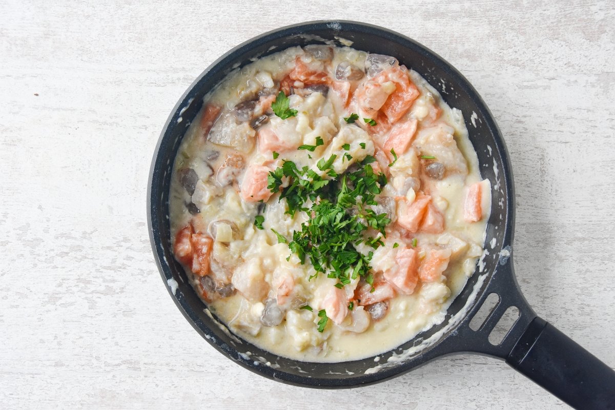Añadimos el pescado a la bechamel junto al perejil