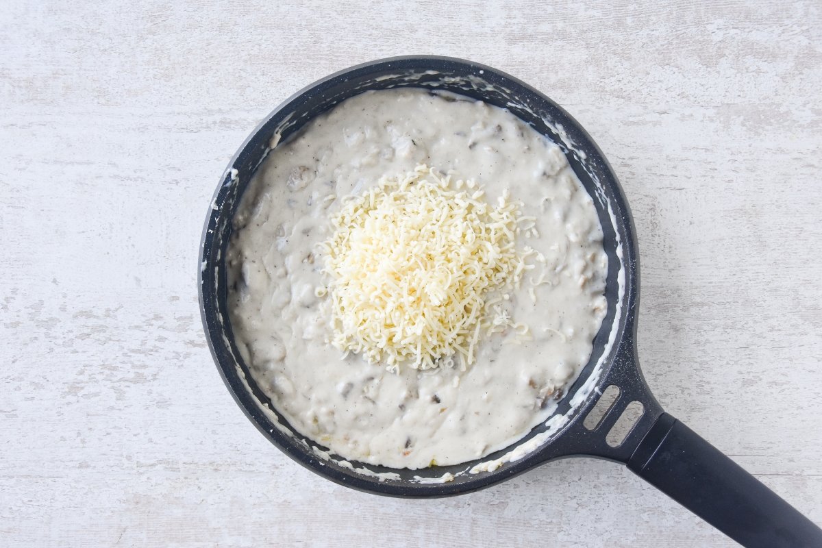 Añadimos el queso rallado a la masa de las croquetas de setas