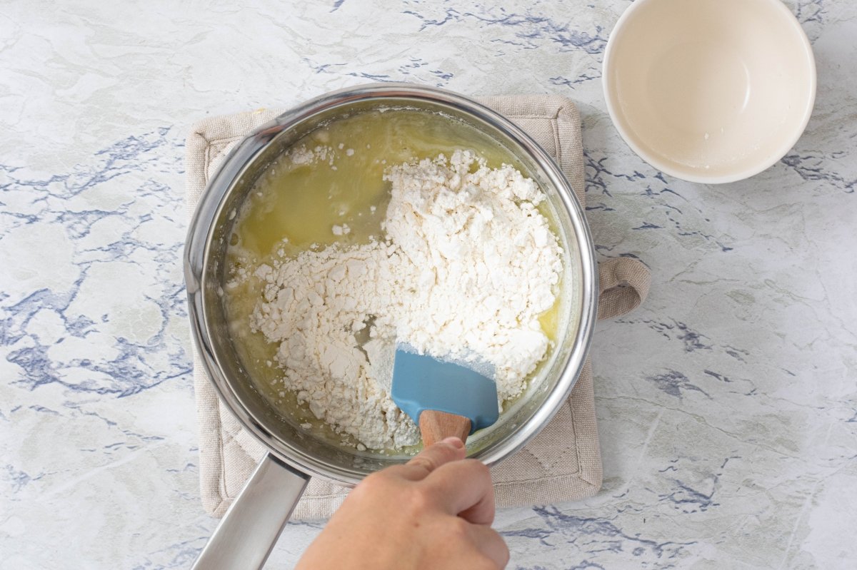 Añadimos la harina a la masa de los profiteroles de crema