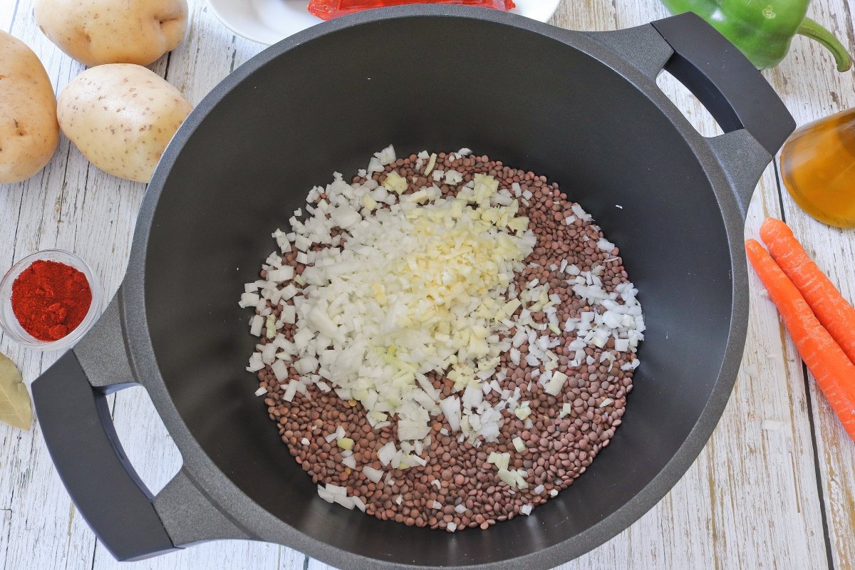 Añadir a la olla de las lentejas con chorizo y patata la cebolla y los ajos
