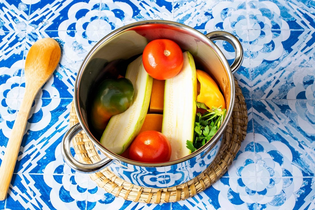Añadir calabacines, pimientos, tomates y hierbas a la cuscusera para el cuscús de verduras