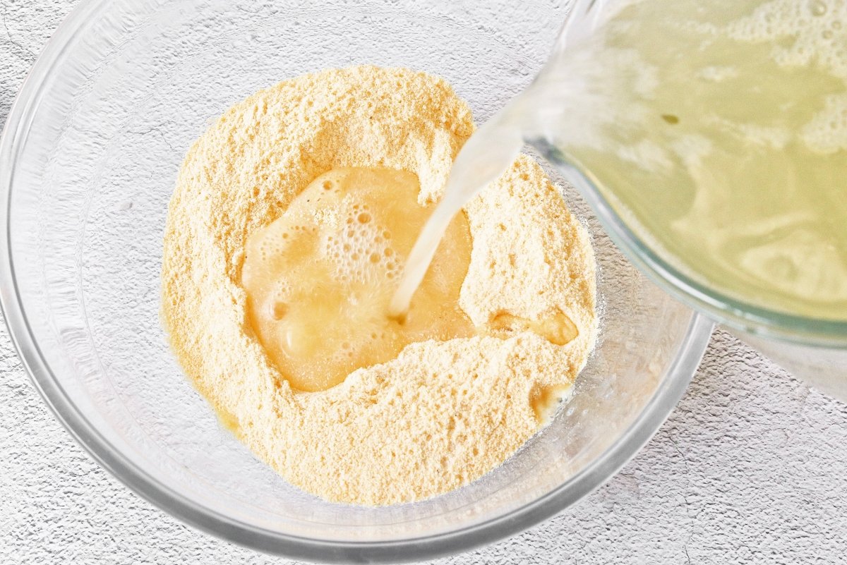 Añadir caldo al maíz para la masa de los tamales colombianos