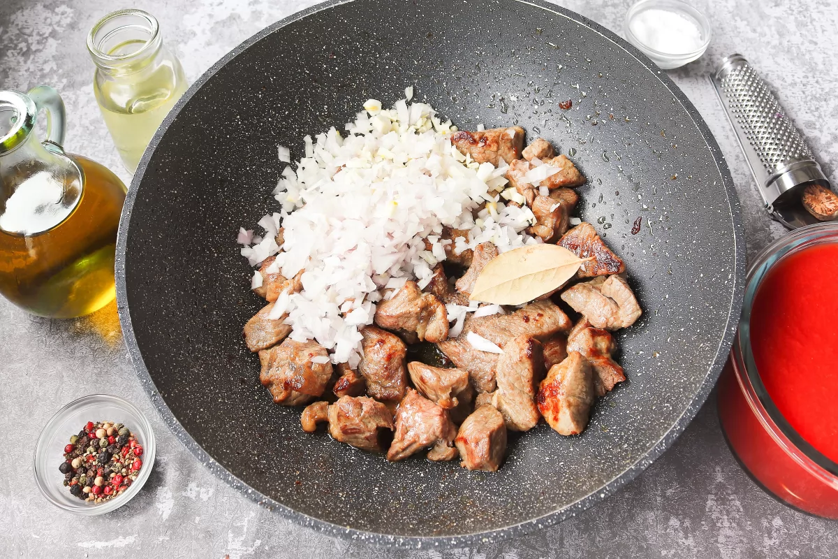 Añadir cebolla, ajo y laurel carne de ternera con cebolla