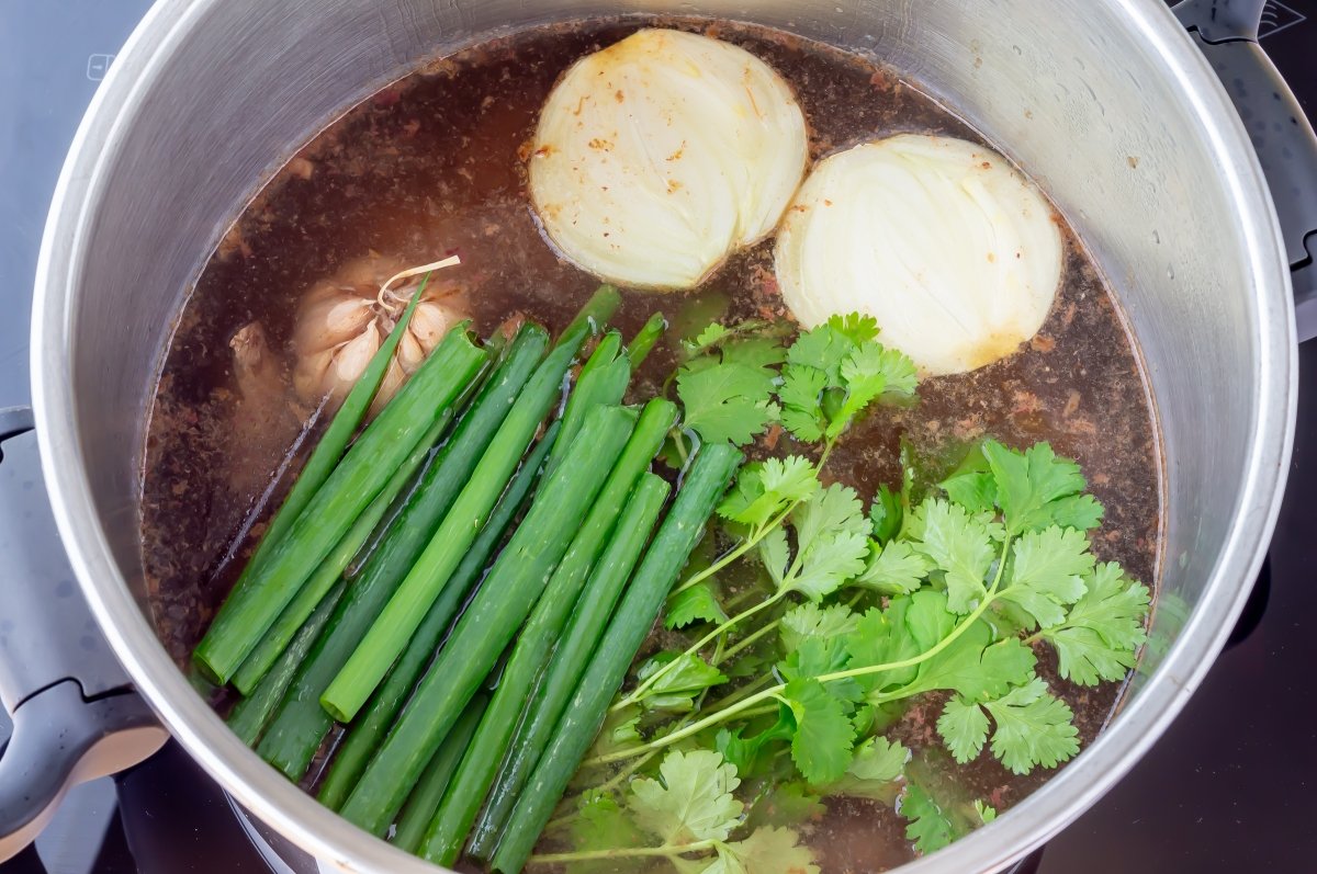 Añadir el agua y los aromáticos para el sancocho colombiano