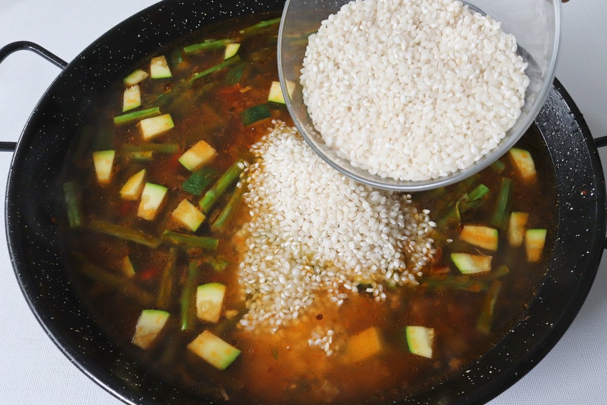 Añadir el arroz a la paella de verduras