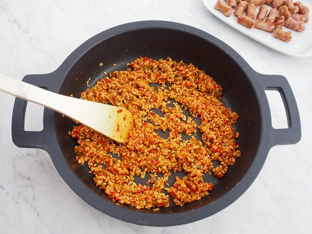 Añadir el arroz al sofrito del arroz con salchichas