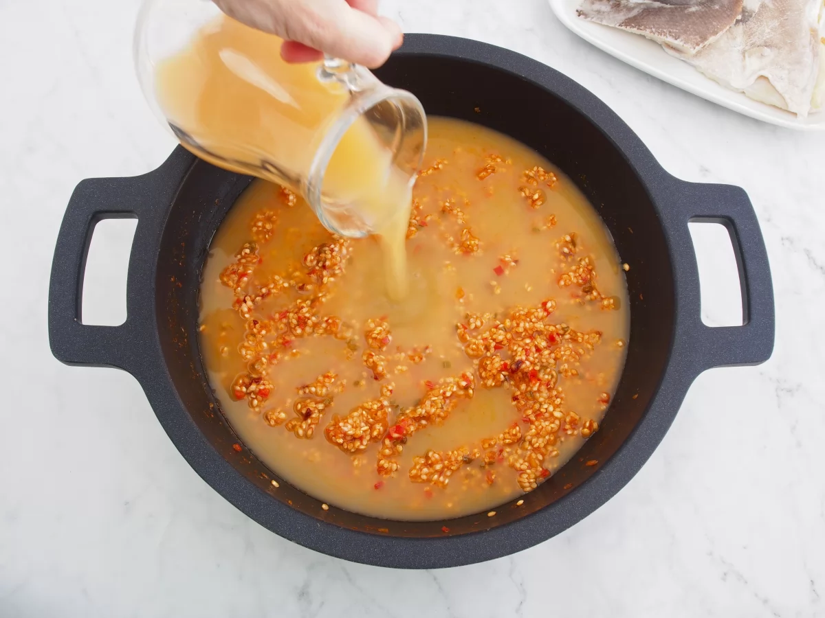 Añadir el caldo de pescado para cocinar el arroz con bacalao