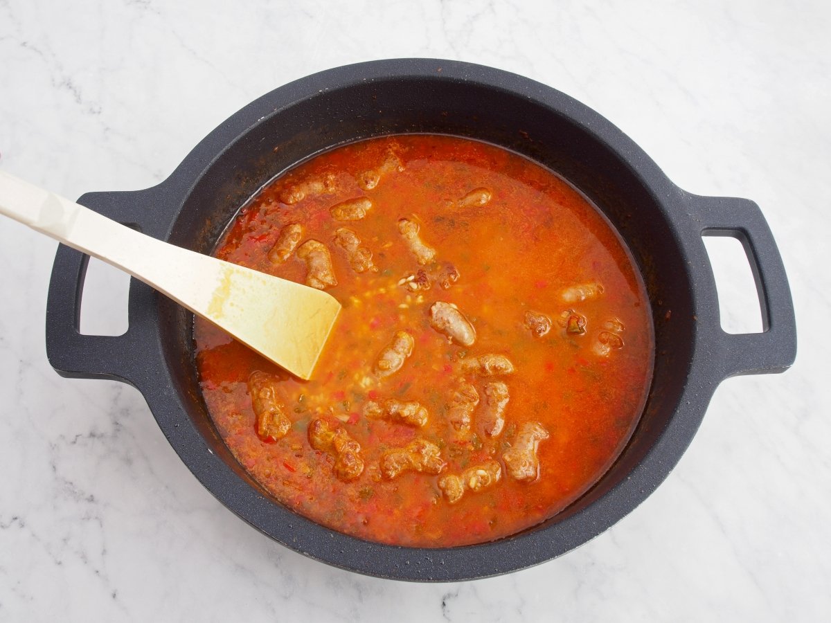 Añadir el caldo de pollo y las salchichas para el arroz con salchichas