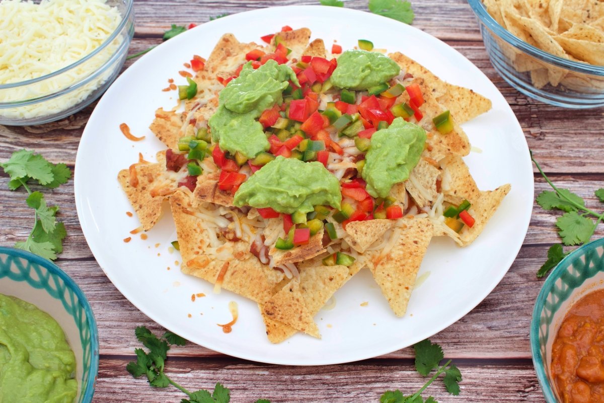 Añadir el guacamole sobre los nachos para seguir preparando los nachos mexicanos con queso, guacamol
