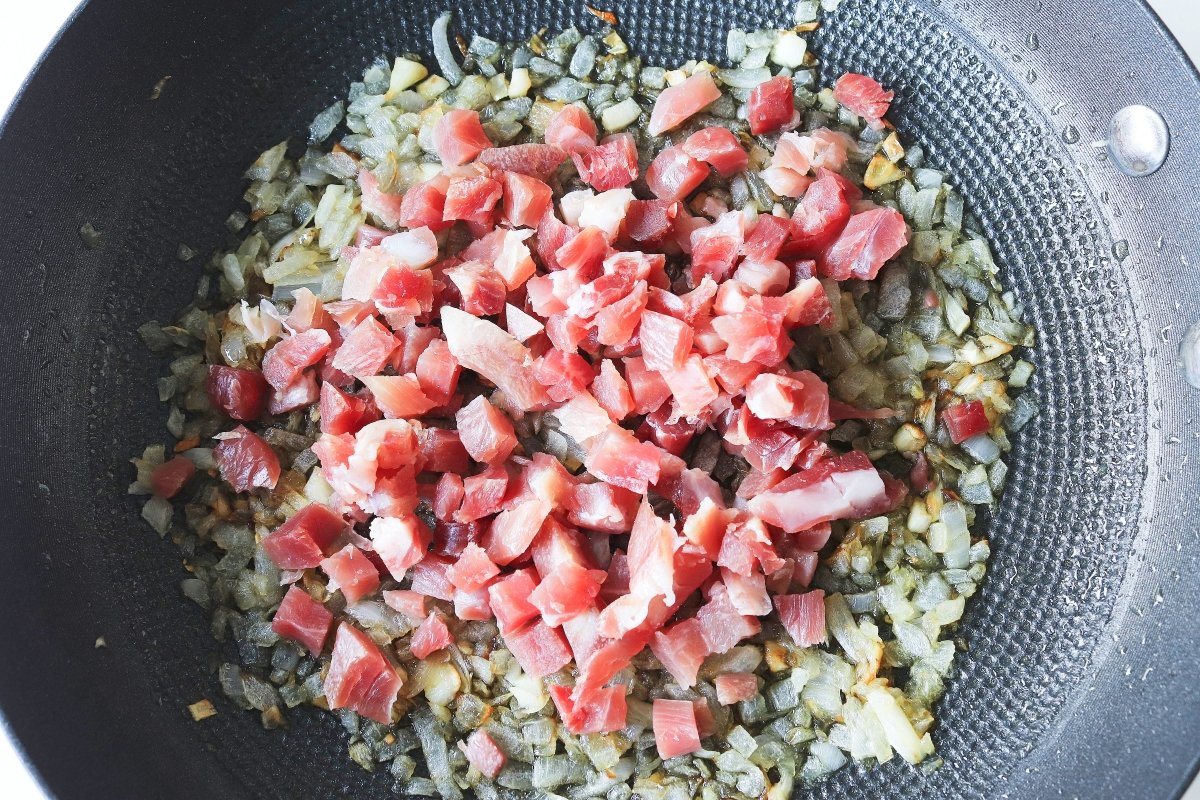 Añadir el jamón a las verduras pochadas para las alcachofas con jamón