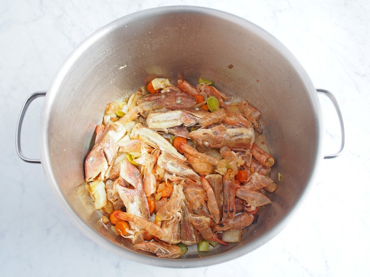 Añadir el pescado y las cabezas de langostinos al sofrito del caldo de la sopa de marisco