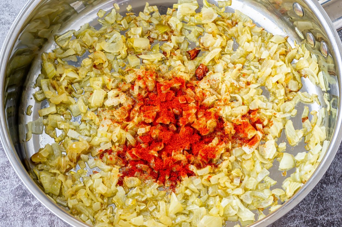 Añadir el pimentón al sofrito de los cangrejos de río en salsa