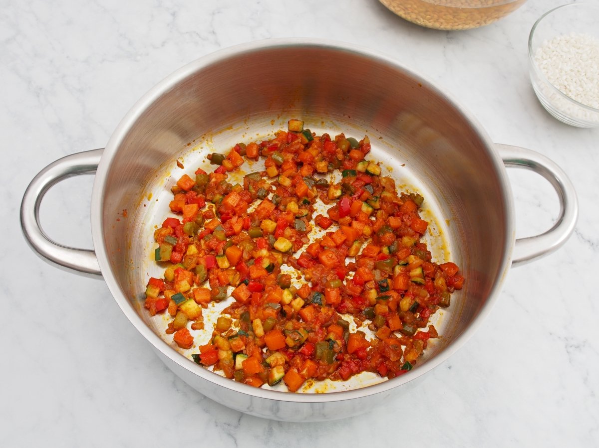 Añadir el pimentón y el tomate al sofrito de las lentejas con arroz