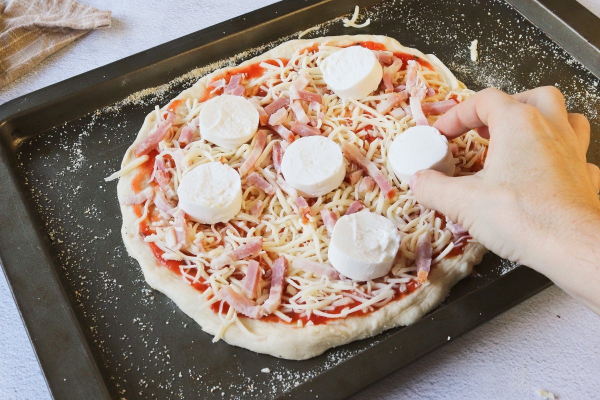 Añadir el queso de cabra a la pizza con bacon