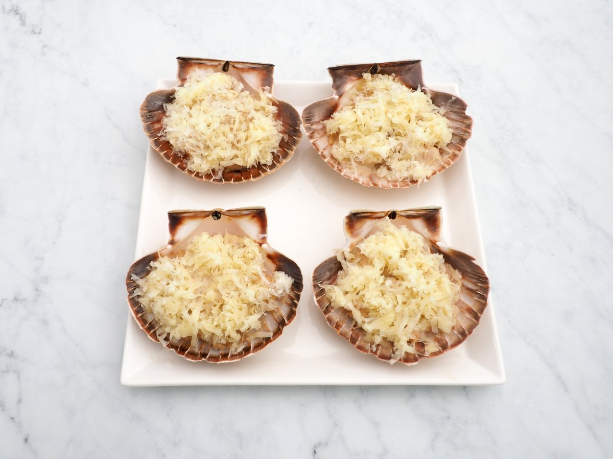 Añadir el queso rallado por encima de las vieiras